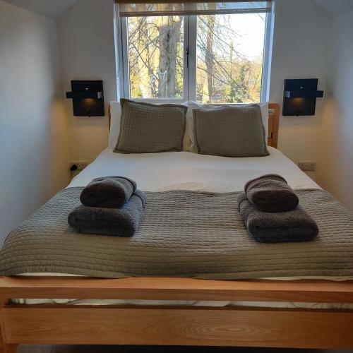 a bed with towels on it with a window at Delightful & Picturesque Modern Detached Apartment, Next to Chester Zoo, Near Park and Ride to City Centre in Chester