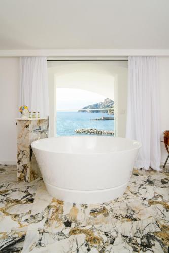 a white bath tub in a room with a view of the ocean at Palazzo Don Salvatore in Amalfi