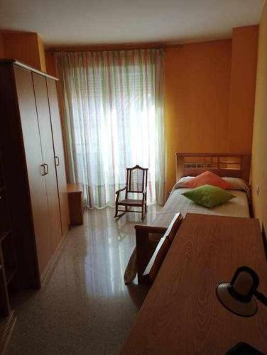 1 dormitorio con 2 camas y ventana con silla en La casa de Ainhoa, en Teruel