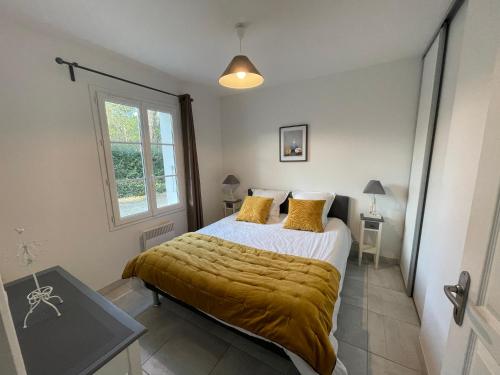 Un dormitorio con una cama con una manta amarilla. en Parad'iles, en Dolus d'Oléron