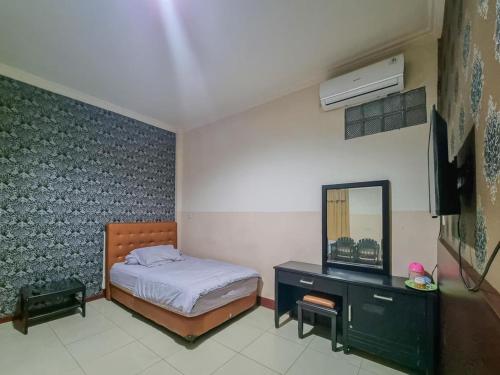 1 dormitorio con cama, tocador y espejo en Hotel Halmahera Palangkaraya Mitra RedDoorz en Palangkaraya