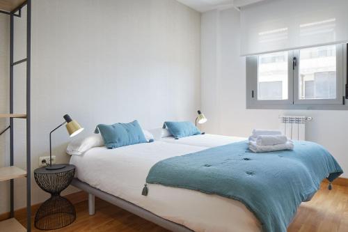- une chambre blanche avec un grand lit et des oreillers bleus dans l'établissement The Rentals Collection - Urumea II, à Saint-Sébastien