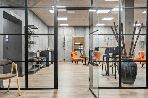 a room with glass doors and chairs and tables at Best Western Royal Holstebro in Holstebro