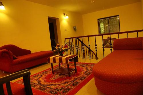 a living room with a red couch and a chair at New Ooty View Cottage in Ooty