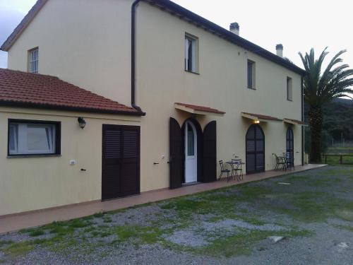 a white house with black doors and a yard at Agriturismo Ristorante Monte Argentario in Monte Argentario
