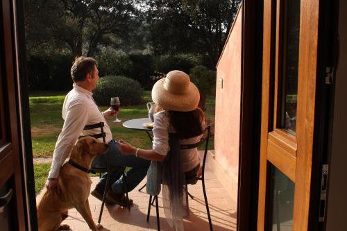 a man and a woman sitting at a table with a dog at Agriturismo Ristorante Monte Argentario in Monte Argentario