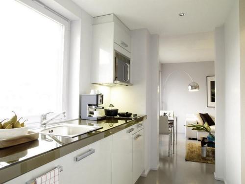 a white kitchen with a sink and a counter at VISIONAPARTMENTS Binzmühlestrasse 48 - contactless check-in in Zürich