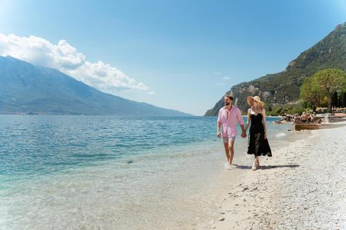 Un uomo e una donna che camminano sulla spiaggia di Hotel Du Lac a Limone sul Garda