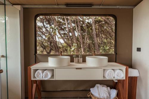 a bathroom with two sinks and a window at Drift Off Grid Luxury Eco Glamping in Tarakohe