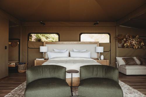 a bedroom with a bed and two chairs at Drift Off Grid Luxury Eco Glamping in Tarakohe