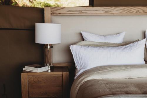 a bedroom with a bed and a lamp on a night stand at Drift Off Grid Luxury Eco Glamping in Tarakohe