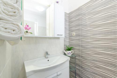 een witte badkamer met een wastafel en een spiegel bij Slavka in Crikvenica