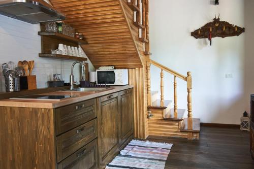 uma cozinha com armários de madeira, um lavatório e uma escadaria em Cabana Rose House em Borşa