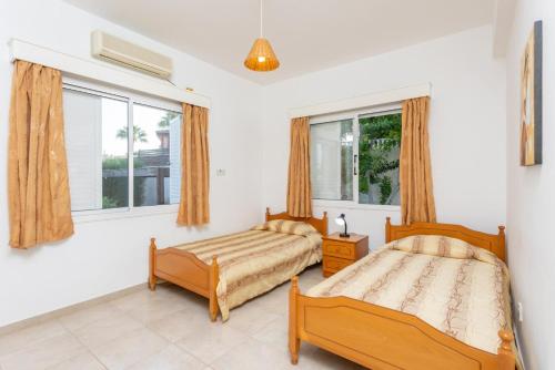 a bedroom with two beds and a window at Villa Lela Pente in Peyia