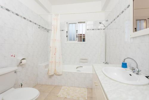 a white bathroom with a sink and a tub and a toilet at Villa Lela Pente in Peyia