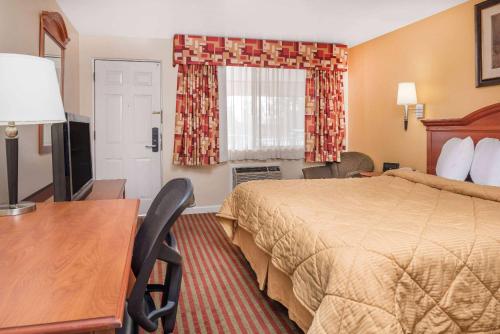 a hotel room with a bed and a desk at Travelodge by Wyndham Klamath Falls in Klamath Falls