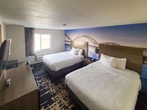 a hotel room with two beds and a desk at Clarion Pointe Bettendorf - Quad Cities in Bettendorf