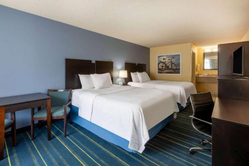 a hotel room with two beds and a desk at Days Inn by Wyndham Charles Town in Charles Town