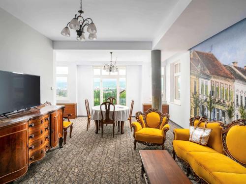 uma sala de estar com uma mesa e mobiliário amarelo em Mercure Medias Binderbubi Hotel And Spa em Mediaş