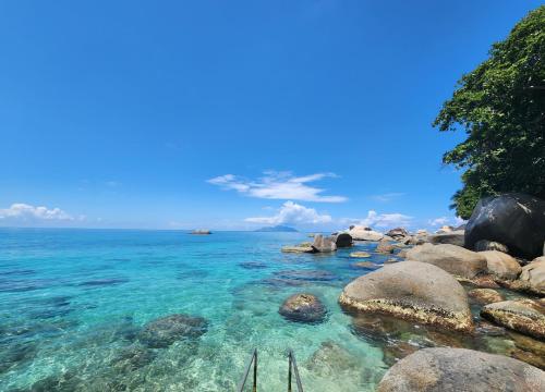 a beach with rocks and the ocean on a clear day at Marquise & Infinity villas in Glacis