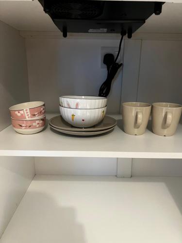a shelf with four bowls and plates on it at Ipoh Peaceful Onsen studio Lost World Tambun in Tambun