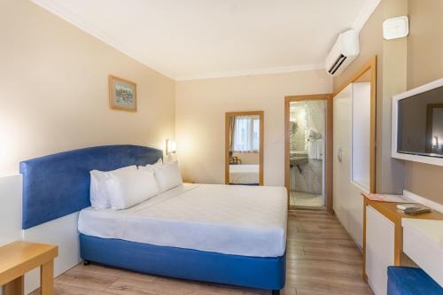 1 dormitorio con 1 cama azul y TV en L'ancora Beach Hotel, en Kemer
