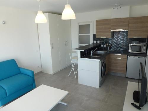 un salon avec un canapé bleu et une cuisine dans l'établissement Studio de charme, piscine et mer à pieds, à Six-Fours-les-Plages