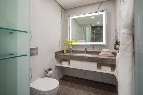 a bathroom with a sink and a toilet and a mirror at voco Dubai The Palm by IHG in Dubai