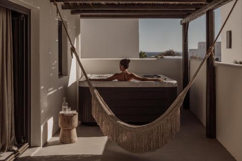 Casa Cook Mykonos - Adults Only في أورنوس: رجل في حوض استحمام على أرجوحة في الغرفة