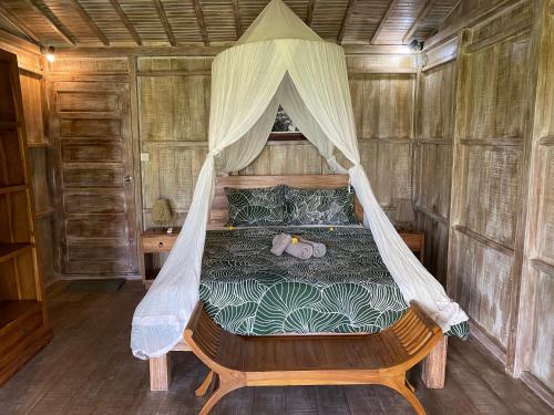 Schlafzimmer mit einem Bett mit Moskitonetz in der Unterkunft Wooden House and Spa Ubud in Ubud
