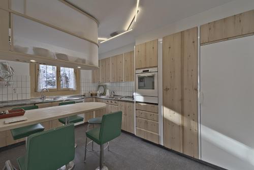 a kitchen with wooden cabinets and green chairs at Chesa Chavriol - Samedan in Samedan