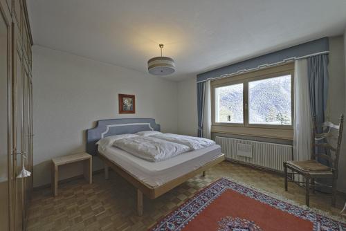 a bedroom with a bed and a large window at Chesa Chavriol - Samedan in Samedan