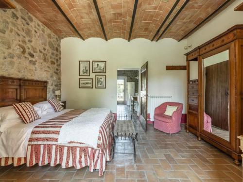 een slaapkamer met een groot bed en een stoel bij Cozy Villa in Castiglione D'orcia Italy with Private Pool in Castiglione dʼOrcia