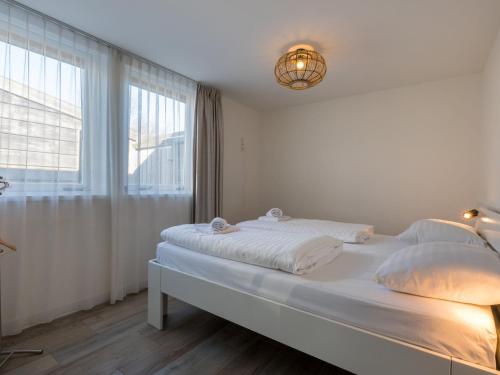 a white bedroom with a large bed and a window at Holiday Home in Zeeland Family-Friendly in Serooskerke