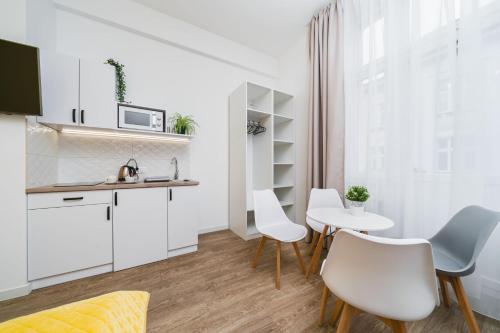 uma cozinha com armários brancos e uma mesa e cadeiras em Bagel Residence Old Town na Cracóvia