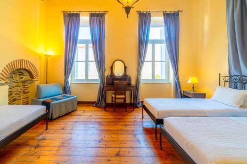 a room with two beds and a chair and a mirror at Archontiko Eleni Hotel in Andros