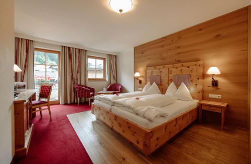 Schlafzimmer mit einem großen Bett mit einem Kopfteil aus Holz in der Unterkunft Hotel Alte Post in Großarl