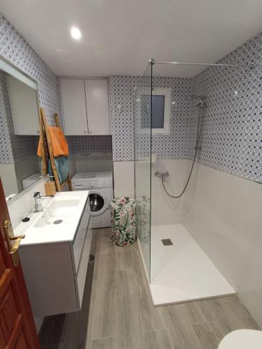 ein Badezimmer mit einer Dusche, einem Waschbecken und einer Waschmaschine in der Unterkunft Strelitzia in Puerto del Carmen