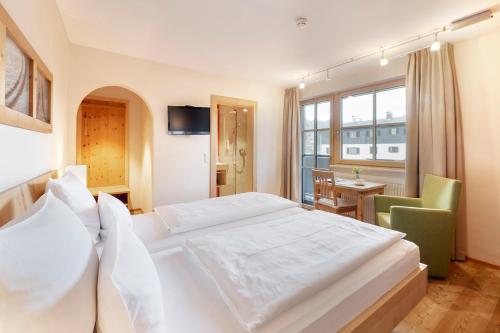 a bedroom with a large white bed and a desk at Gästehaus Bramböck in Bad Häring