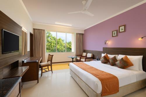 a hotel room with a bed and a television at Sangam Hotel, Thanjavur in Thanjāvūr