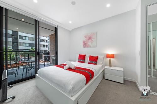 a white bedroom with a large bed with red pillows at KOZYGURU Penrith Cosy 2BED 2BATH APT + FREE Parking NPE081 in Penrith