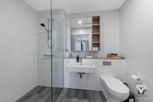 a white bathroom with a toilet and a sink at KOZYGURU Penrith Cosy 2BED 2BATH APT + FREE Parking NPE081 in Penrith