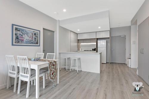 a kitchen and dining room with a table and chairs at KOZYGURU Penrith Cosy 2BED 2BATH APT + FREE Parking NPE081 in Penrith