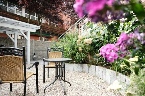 a patio with two chairs and a table and flowers at Apartments zur alten Konditorei in Schwerin
