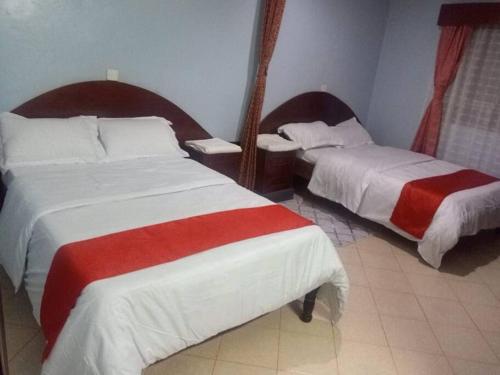 Habitación de hotel con 2 camas con sábanas rojas y blancas en Greton Holiday Villa en Meru
