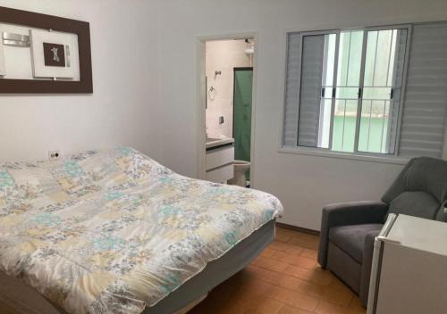 a bedroom with a bed and a chair and a window at WR7 Hostel in São Bernardo do Campo