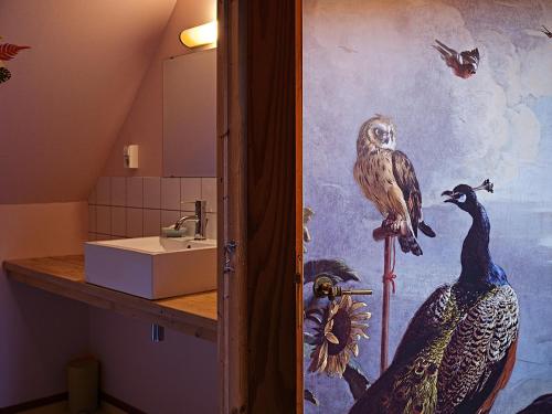 a bathroom with a painting of birds on the wall at JagershuisTexel in Oosterend