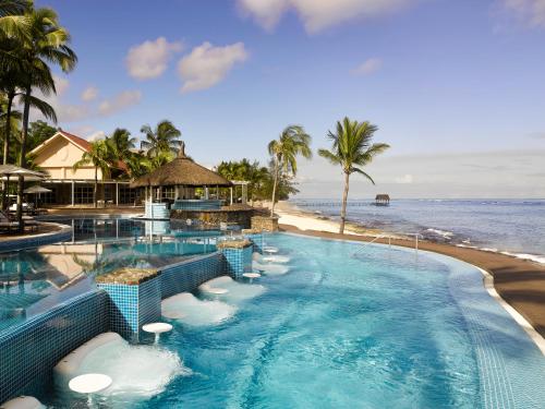 a swimming pool next to a beach with the ocean at Le Meridien Ile Maurice in Pointe aux Piments