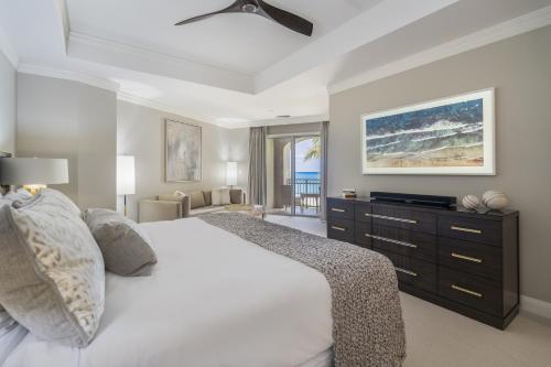 a bedroom with a large white bed with a dresser at Luxurious Condo with Private Ocean Views Directly on Seven Mile Beach condo in Dog City