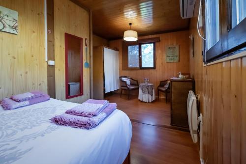 una camera da letto con letto bianco in una camera in legno di Casa Rural La Canadiense Log Cabin a Buenache de la Sierra